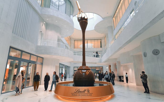 Lindt Chocolate Museum interior with large chocolate fountain and visitors exploring.
