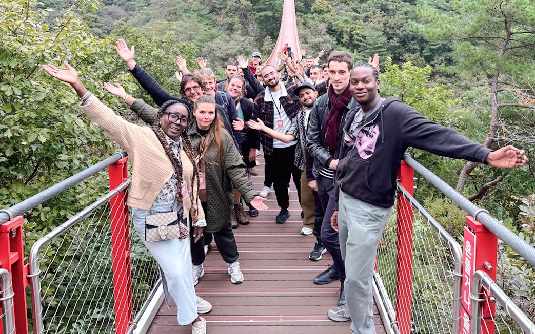 Tour group waving on a suspension bridge over a forested valley during DMZ tour.