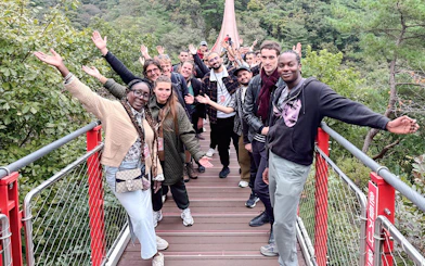 Tour group waving on a suspension bridge over a forested valley during DMZ tour.