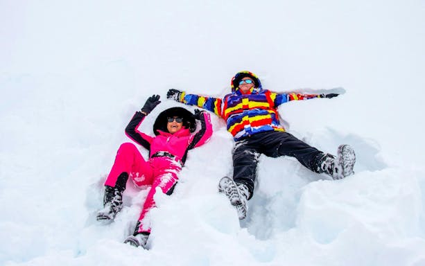 Tourists relaxing in snow at Valle Nevado ski resort, Andes Mountains, Chile.