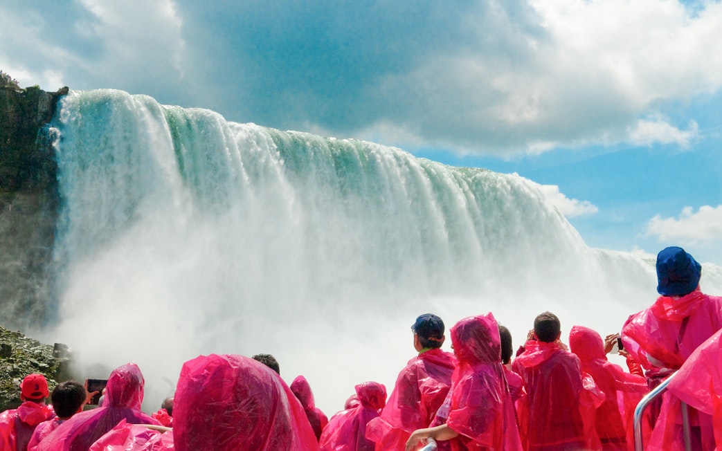 Tourists in pink ponchos view Niagara Falls cascade.