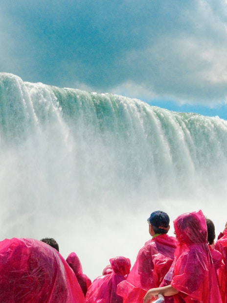 Tourists in pink ponchos view Niagara Falls cascade.