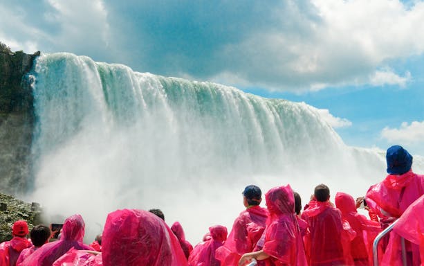 Tourists in pink ponchos view Niagara Falls cascade.