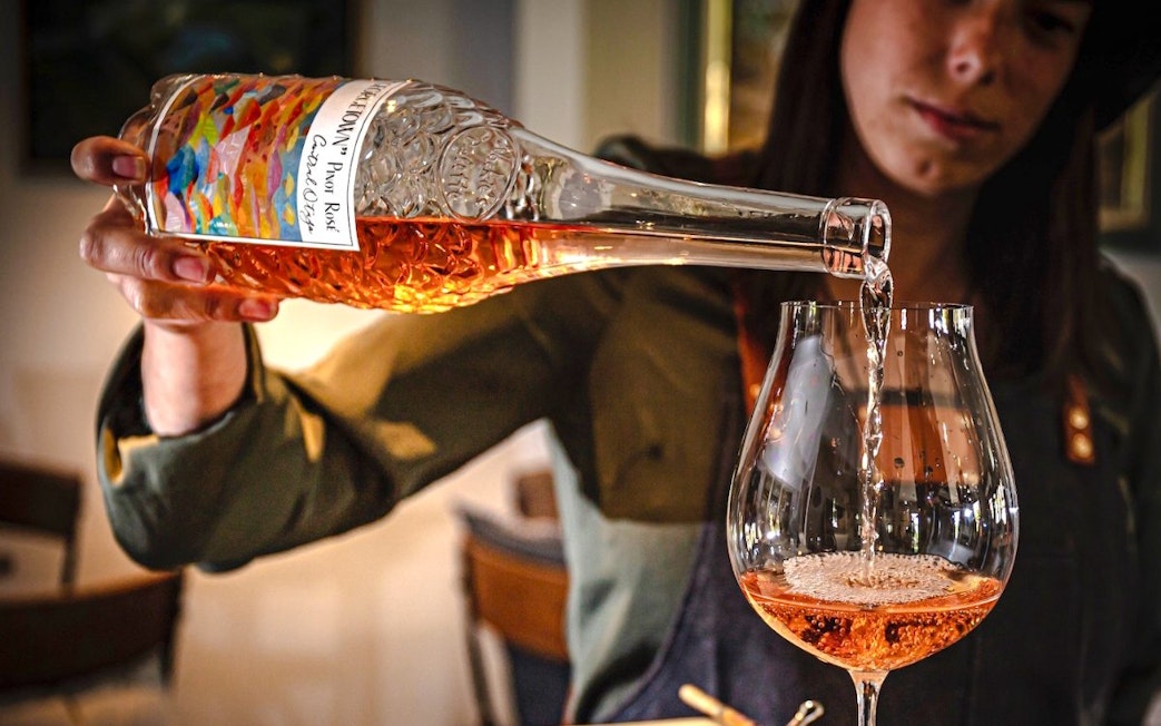 Pouring rosé wine into a glass during a Queenstown wine tour.