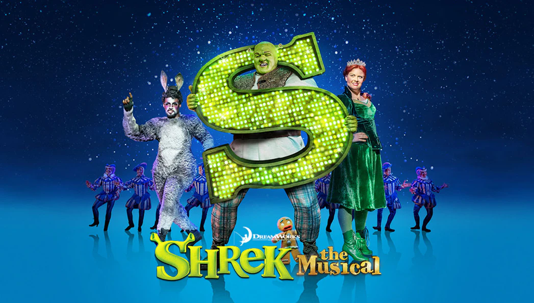 Shrek The Musical characters on stage with a large green "S" sign.