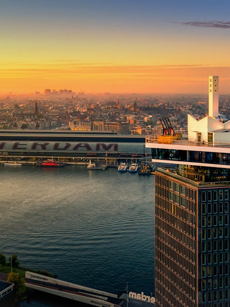 ADAM Lookout tower with Amsterdam skyline at sunset.