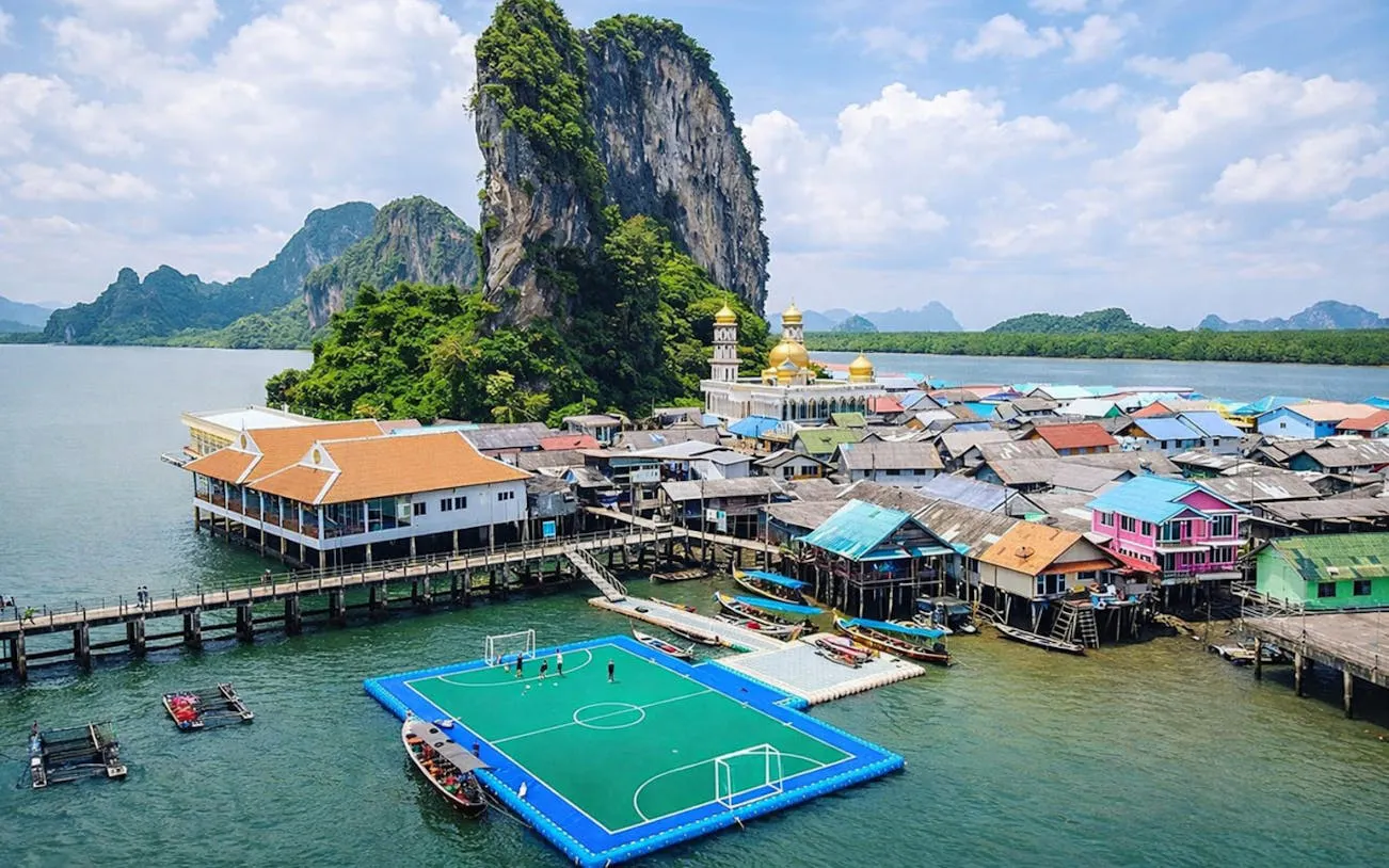 Floating village with a soccer field and limestone cliffs on James Bond Island, Phuket.