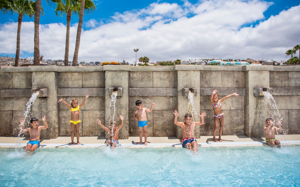 Children playing under water jets at Aqualand Costa Adeje pool.