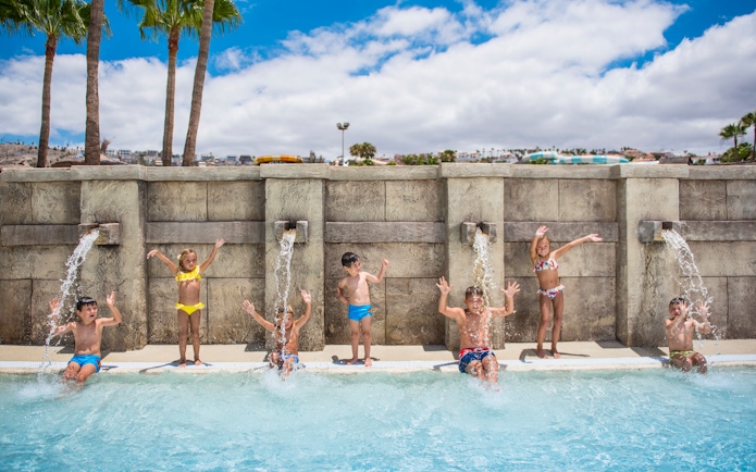 Children playing under water jets at Aqualand Costa Adeje pool.