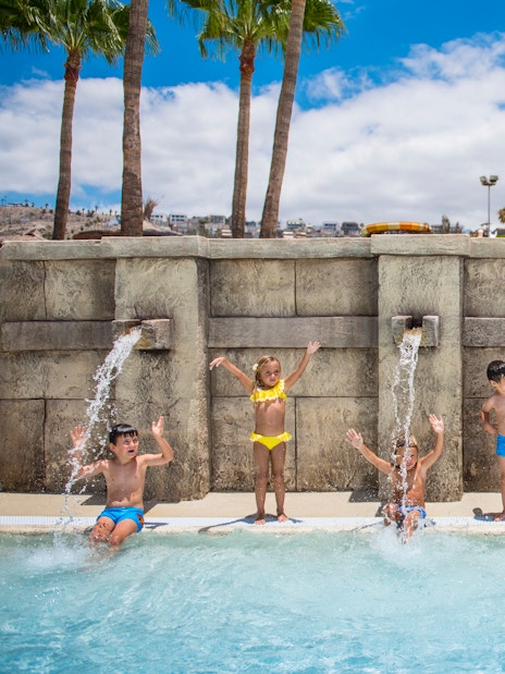 Children playing under water jets at Aqualand Costa Adeje pool.