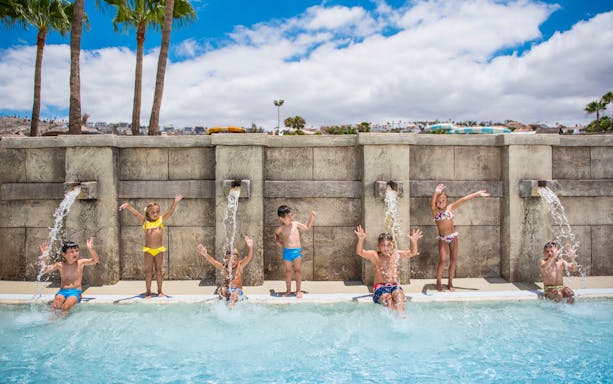 Children playing under water jets at Aqualand Costa Adeje pool.