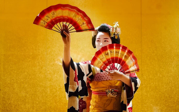 Geisha performing with fans in traditional attire, Kyoto.