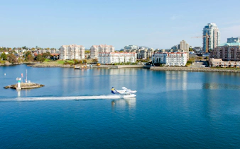 Seaplane taking off from Victoria harbor with city skyline in the background.