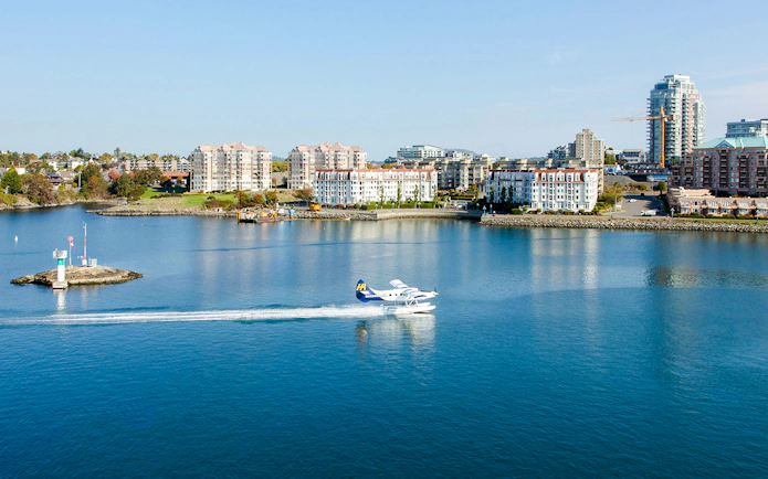 Seaplane taking off from Victoria harbor with city skyline in the background.