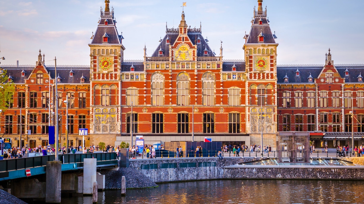 Amsterdam Central Train Station with people walking by the canal.