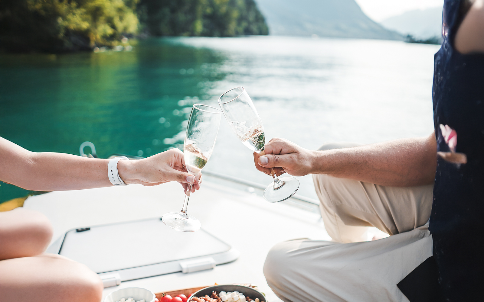 Couple toasting with prosecco on a speedboat in a scenic lake setting.