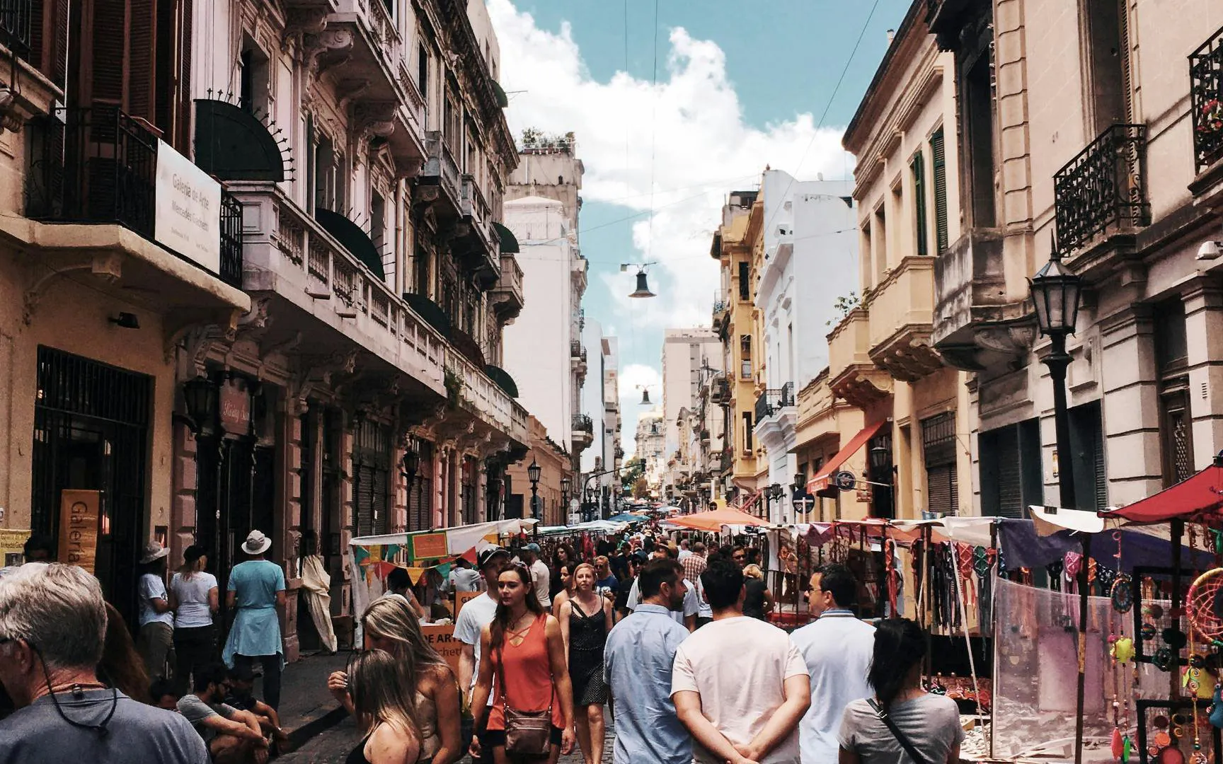 Crowded street market in San Telmo, Buenos Aires, with historic buildings and local vendors.