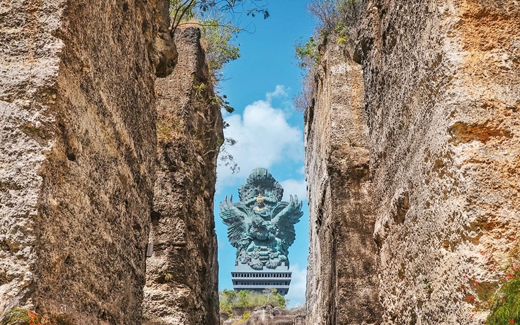 Garuda Wisnu statue framed by rocky cliffs in Bali, Indonesia.
