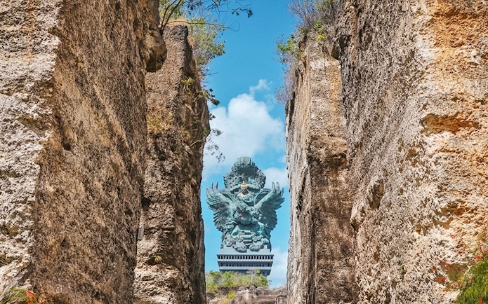 Garuda Wisnu statue framed by rocky cliffs in Bali, Indonesia.