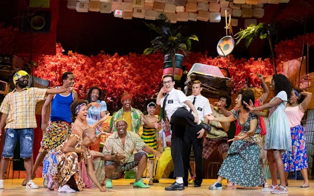 Performers on stage in a vibrant scene from "The Book of Mormon" musical.
