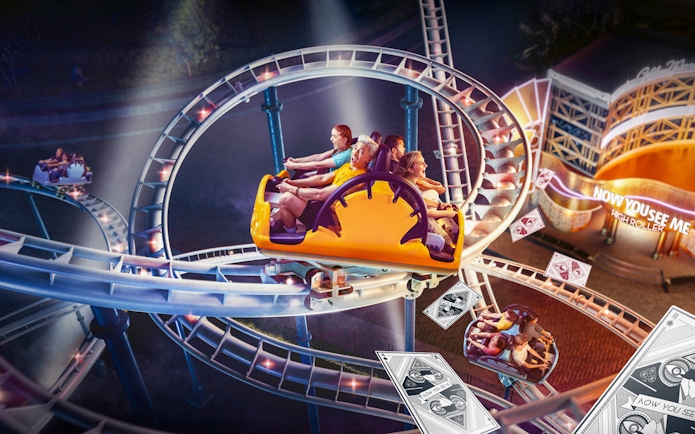 Roller coaster at MOTIONGATE™ Dubai with riders on a loop track at night.
