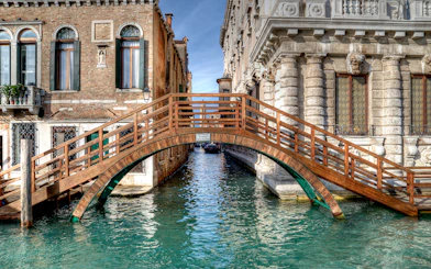 Wooden bridge over canal between historic buildings in Venice near Ca' Rezzonico.