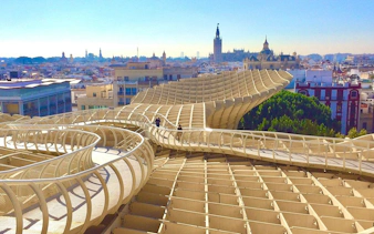Tourists walking on Setas de Sevilla with cityscape in the background.