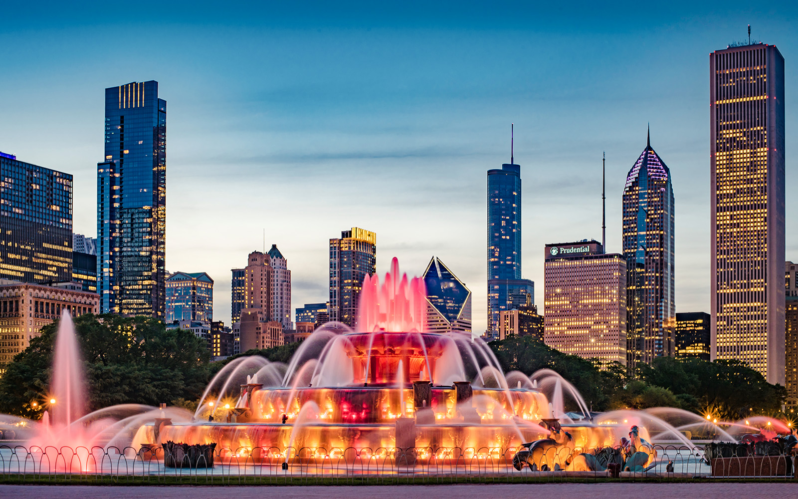 Buckingham Fountain illuminated at dusk with Chicago skyline in the background.
