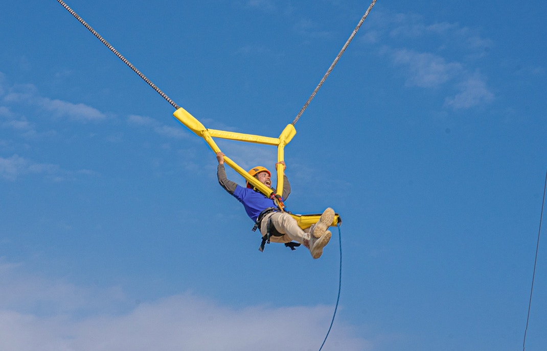 Visitors zip-lining at Hatta Wadi Hub, Dubai, surrounded by rugged mountains.