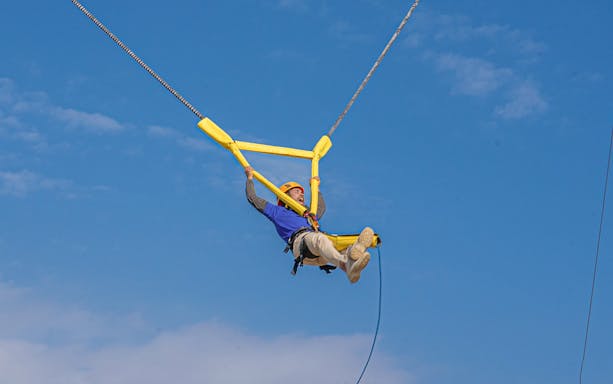 Person enjoying a bungee trampoline at Hatta Wadi Hub under a clear blue sky.
