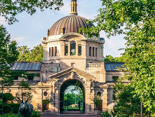 Bronx Zoo entrance with historic dome and archway surrounded by greenery.