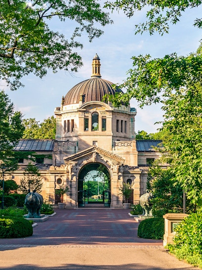 Bronx Zoo entrance with historic dome and archway surrounded by greenery.