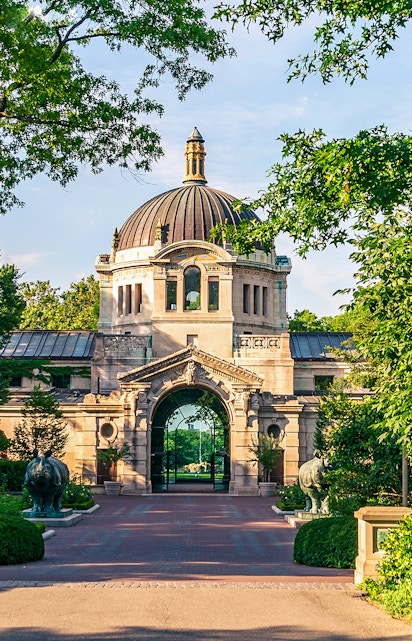 Bronx Zoo entrance with historic dome and archway surrounded by greenery.