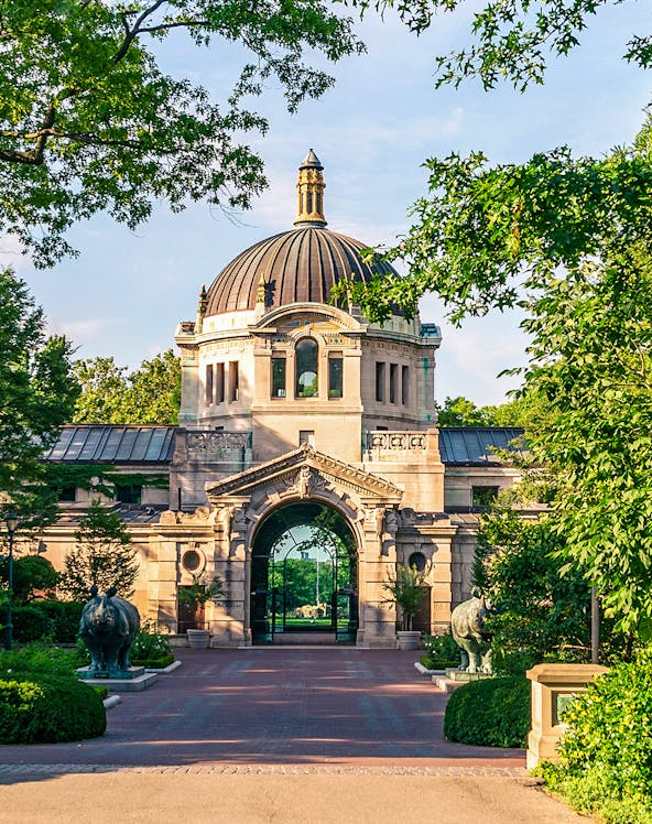 Bronx Zoo entrance with historic dome and archway surrounded by greenery.