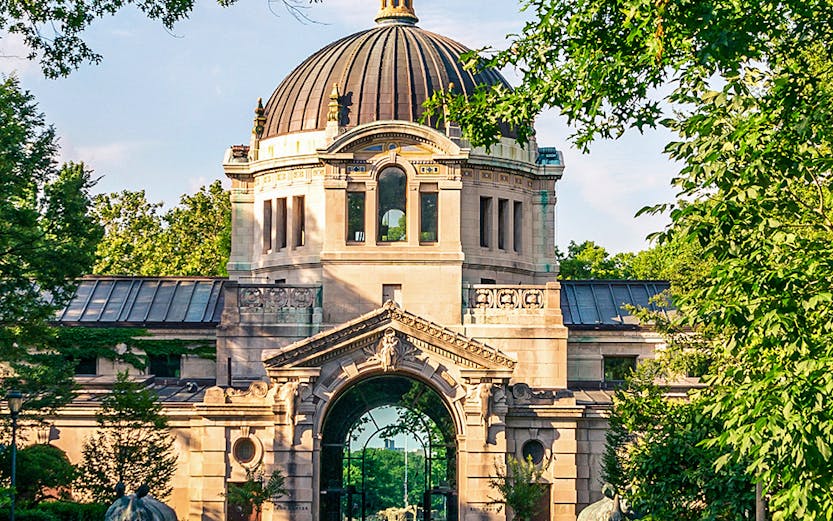 Bronx Zoo entrance with historic dome and archway surrounded by greenery.