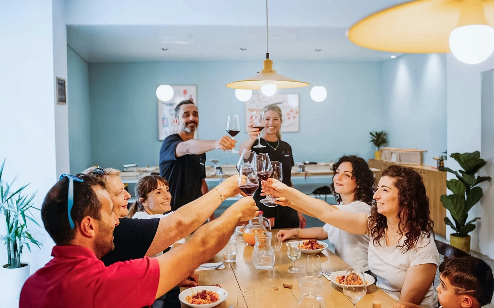 Tourists toasting with wine while cooking with a local chef in a kitchen setting.