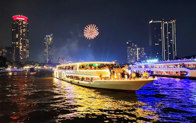Dinner cruise on Chao Phraya River with fireworks and city skyline in Bangkok.