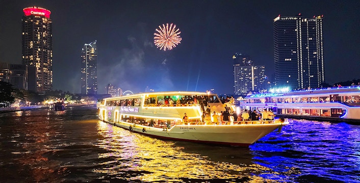 Dinner cruise on Chao Phraya River with fireworks and city skyline in Bangkok.