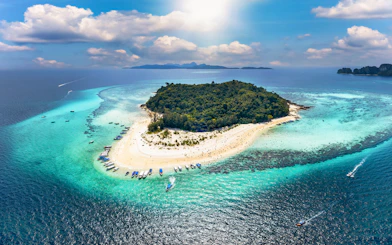 Aerial view of Bamboo Island with boats along the sandy shore and turquoise waters.