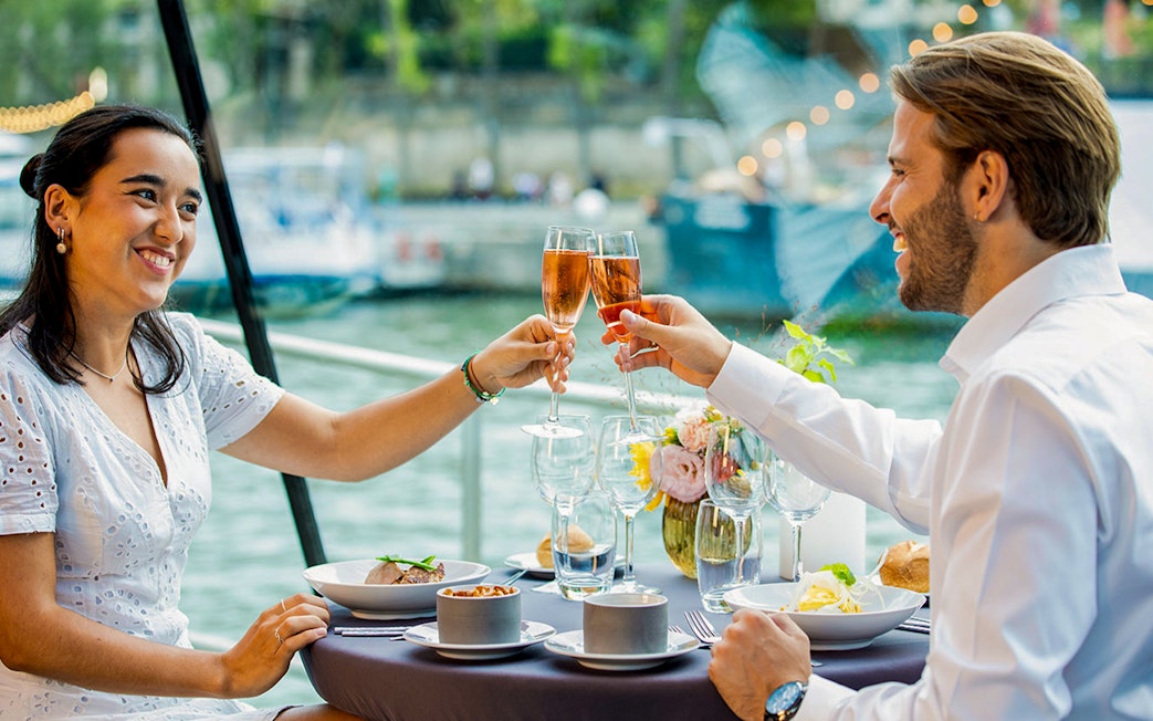 Couple toasting with champagne on a Seine River dinner cruise in Paris.