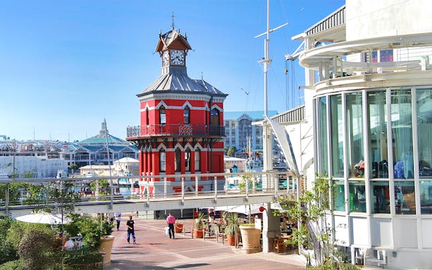 Clock tower at V&A Waterfront, Cape Town, with HopOn HopOff bus tour route nearby.