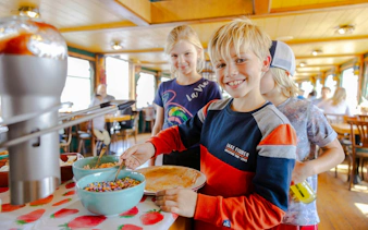 Children enjoying toppings on Dutch pancakes during a cruise in Amsterdam.