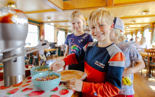 Children enjoying toppings on Dutch pancakes during a cruise in Amsterdam.