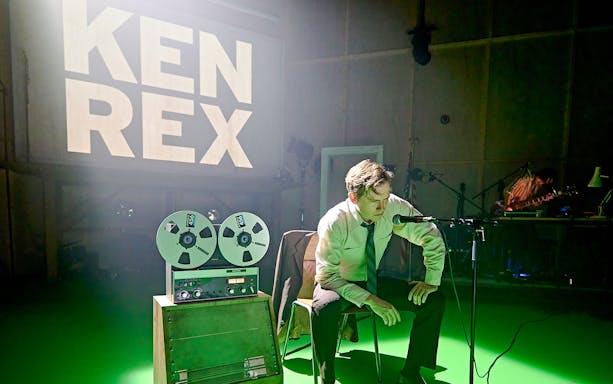 Kenrex stage performance with a man speaking into a microphone, reel-to-reel tape recorder in view.