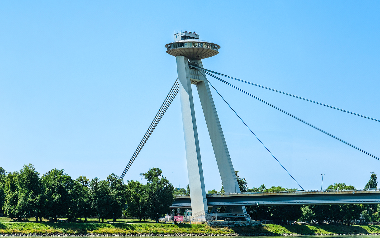 UFO Tower on Slovak Resistance Bridge in Bratislava, Slovakia, with trees below.