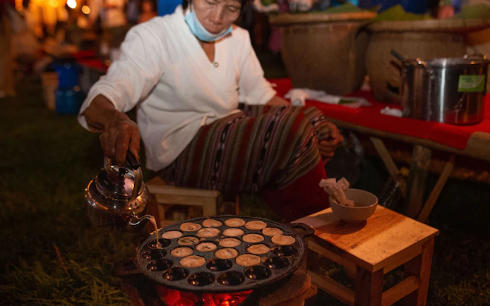 Person preparing traditional snacks at Yeepeng Lanna Festival 2023 in Thailand.