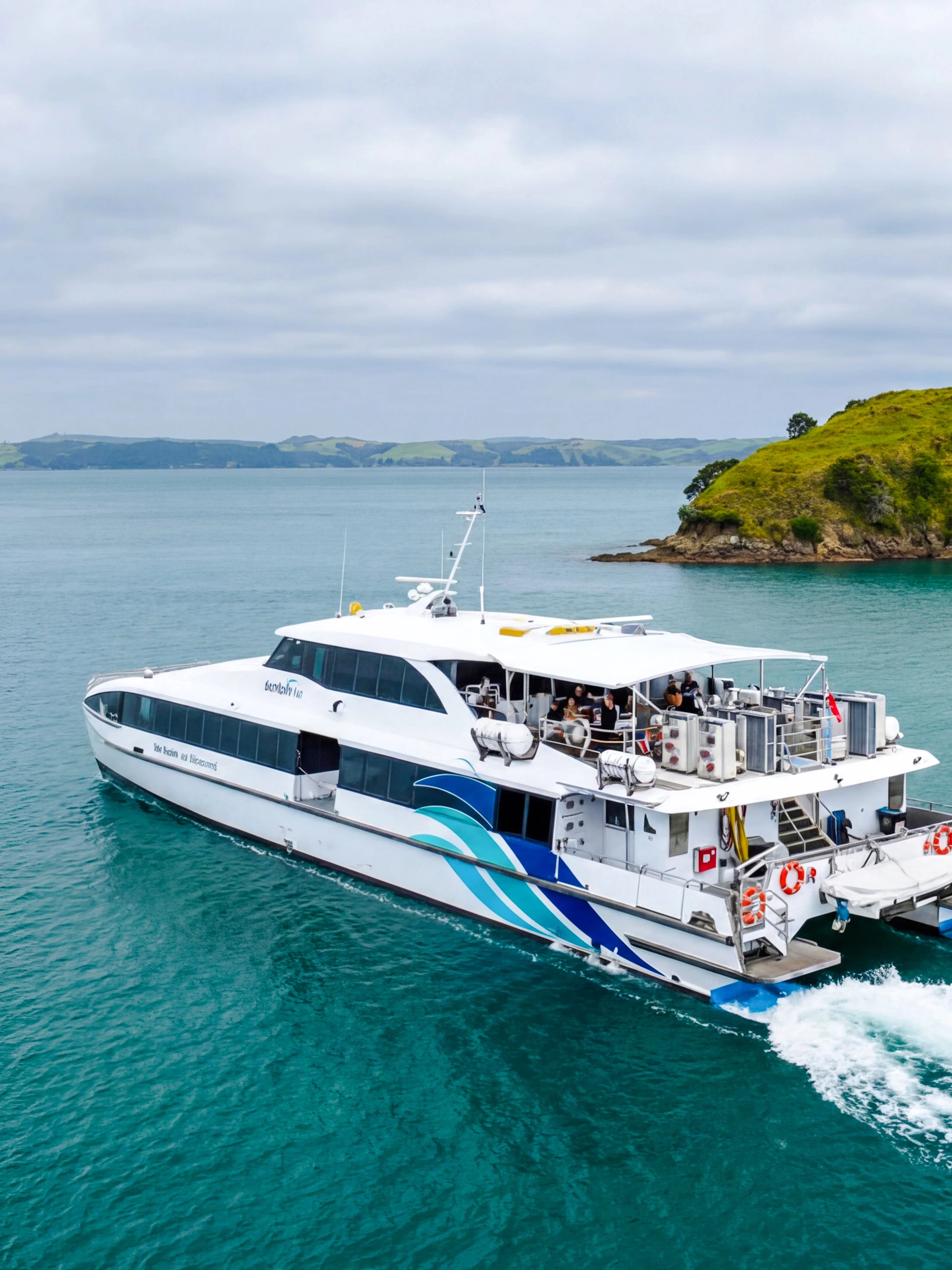 Ferry approaching Rangitoto Island from Auckland across blue waters.