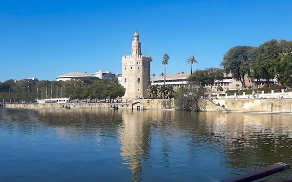 Torre del Oro by the Guadalquivir River in Seville, Spain, with clear blue sky.