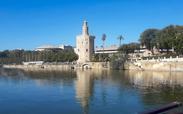 Torre del Oro by the Guadalquivir River in Seville, Spain, with clear blue sky.