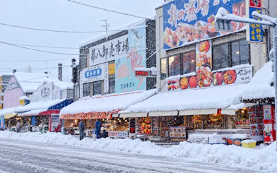 Snow-covered market street in Sapporo, Hokkaido, featuring seafood stalls and local shops.